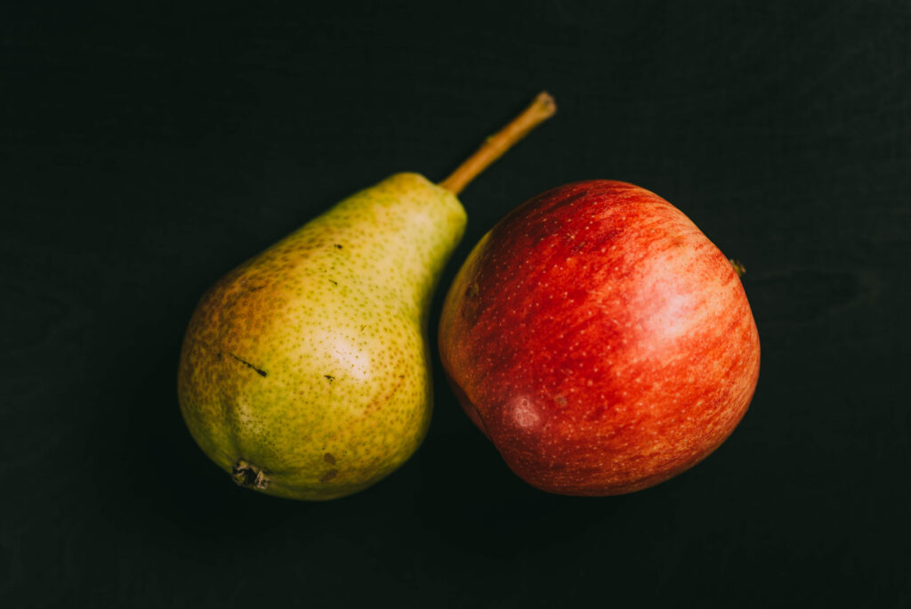 yellow pear and red apple on black background