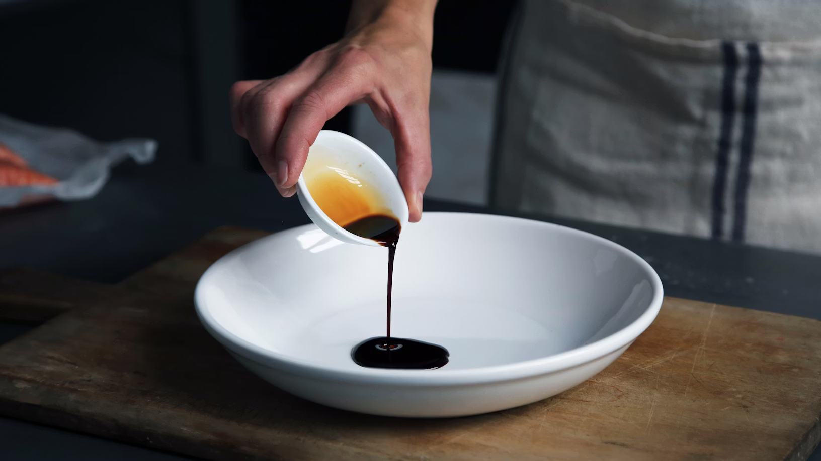 women pouring balsamic vinegar in a white plate